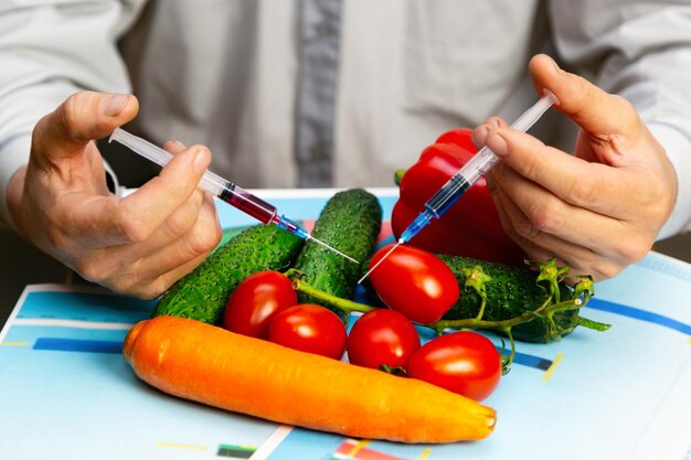 Un hombre inyecta productos químicos en un tomate fertilizantes genéticamente modificados y productos químicos con una jeringa para aumentar