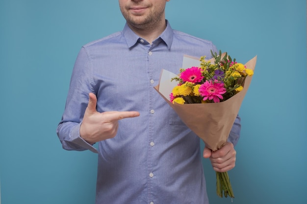 Hombre irreconocible con camisa azul sosteniendo flores como regalo para su madre o novia en el cumpleaños