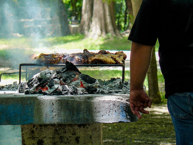 hombre irreconocible cocinando una típica barbacoa argentina