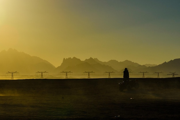 Hombre irreconocible conduciendo quads durante un viaje de safari al atardecer en el desierto árabe no lejos de la ciudad de Hurghada Egipto