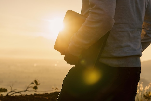 Hombre irreconocible con una laptop caminando al amanecer