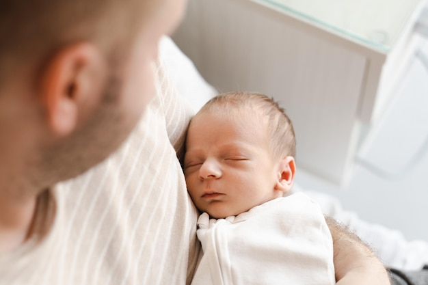 Hombre irreconocible padre sosteniendo niño caucásico peludo brunet lindo bebé recién nacido durmiendoUn niño de dos semanas en la cama en manos masculinasCarelovefelicidad conceptoVista de ángulo alto