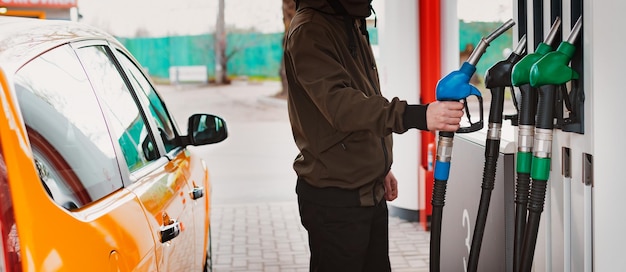 Hombre irreconocible repostando coche de gasolinera llenando combustible de gasolina bencina en coche en gasolinera Concepto de precios altos de gasolina