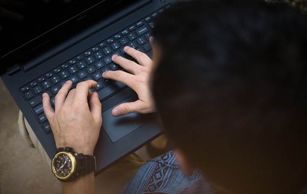 Hombre irreconocible sosteniendo y escrito en la computadora portátil.