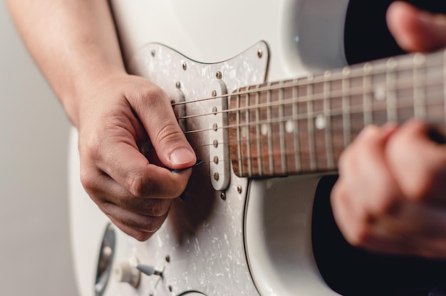 Hombre irreconocible tocando guitarra eléctrica con púa