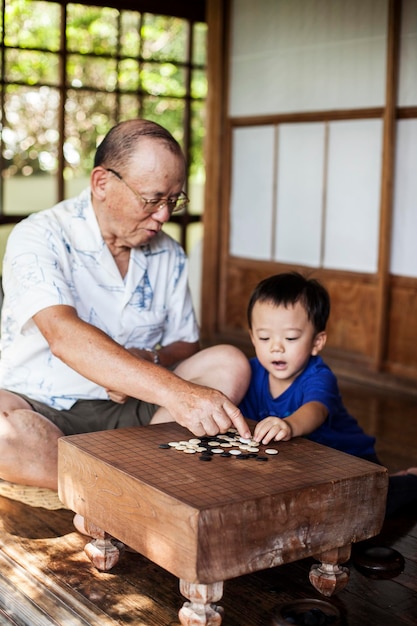 Hombre japonés y niño sentado en el suelo en el porche de la casa tradicional japonesa jugando Go