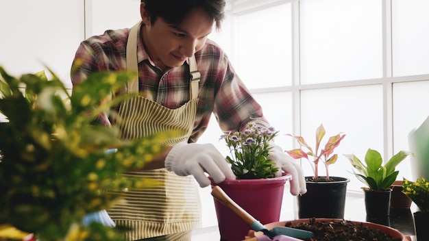 Hombre jardinero feliz cuidando flor en una maceta.