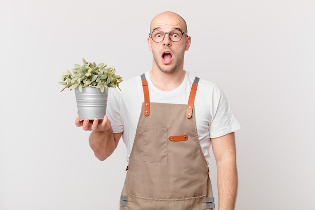 Hombre jardinero que parece muy conmocionado o sorprendido, mirando con la boca abierta y diciendo wow