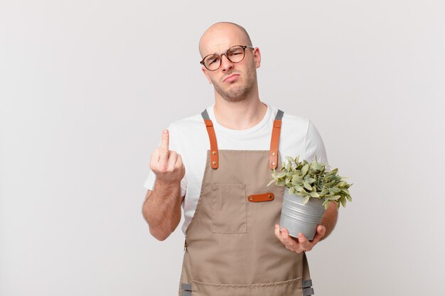 Hombre jardinero que se siente enojado, molesto, rebelde y agresivo, moviendo el dedo medio, contraatacando