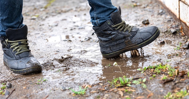 Un hombre con jeans y botas camina por el pantano cuando llueve