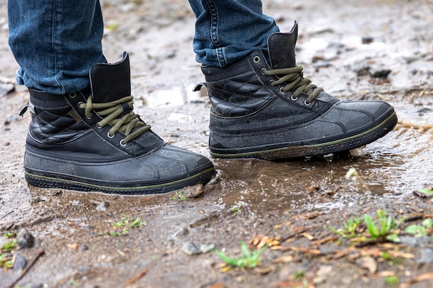 Un hombre con jeans y botas camina por el pantano cuando llueve