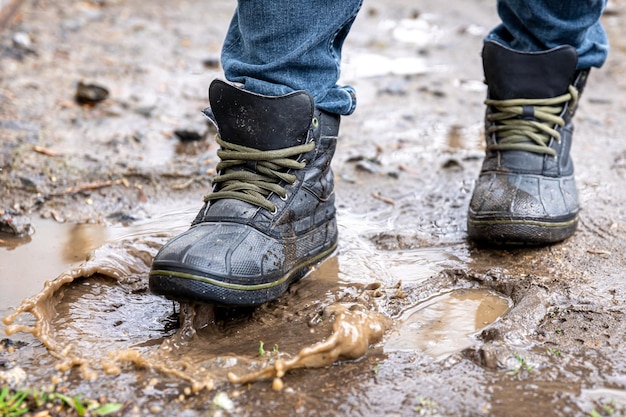 Un hombre con jeans y botas camina por el pantano cuando llueve