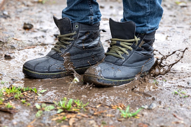 Un hombre con jeans y botas camina por el pantano cuando llueve