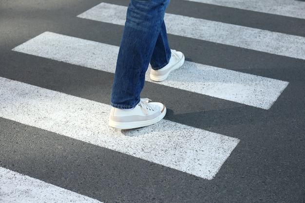 Hombre en jeans y zapatillas caminando por el paso de peatones.