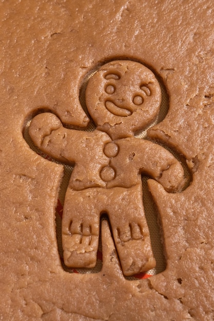 Foto hombre de jengibre tallado en masa de pan de jengibre cruda hacer galletas de jengibre caseras galletas de navidad