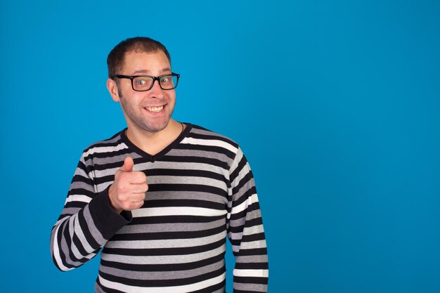 El hombre en jersey está sonriendo contra el fondo azul.