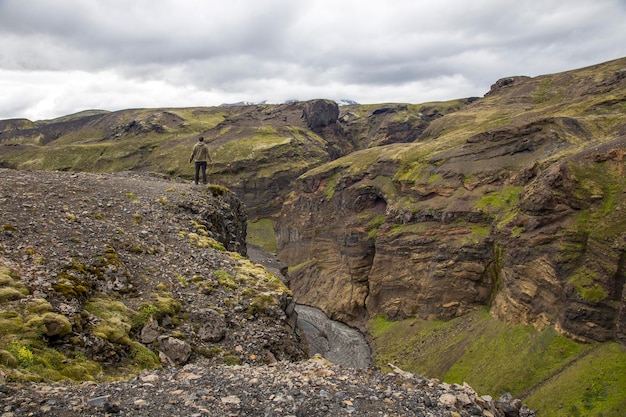 Un hombre joven en un acantilado en el valle de Landmannalaugar en la caminata Islandia