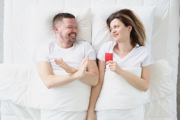 Hombre joven acostado en la cama con la mujer y rechazando los problemas de la vista superior del condón con la potencia en los hombres