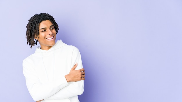 Hombre joven afroamericano rasta sonriendo confiado con los brazos cruzados.