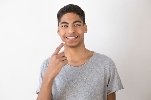 Hombre joven afroamericano sonriente que muestra en los dientes blancos sanos. Concepto de odontologia