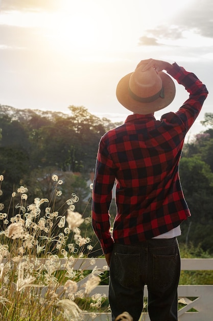 Foto hombre joven agricultor negro trabajando frente a la puerta de los granjeros hombre joven africano con sombrero en la granja con puesta de sol