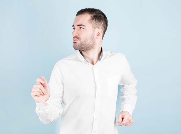 Hombre joven alegre en camisa posando en la pared azul