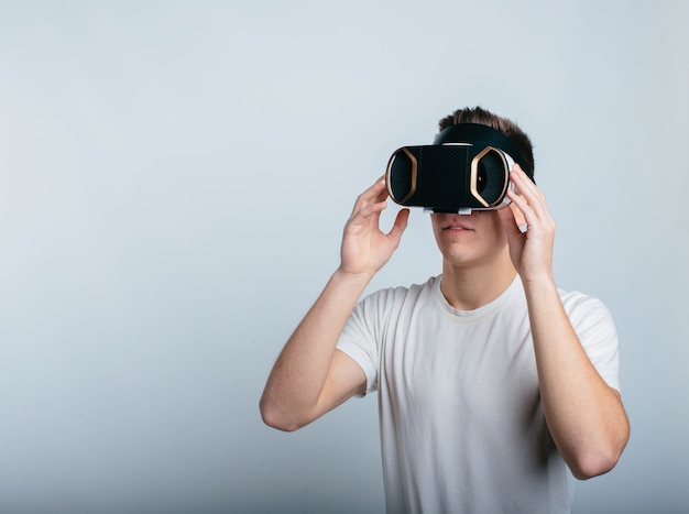 Hombre joven alegre que usa auriculares VR para experimentar la realidad virtual. Independiente en la habitación y aislado sobre fondo blanco. Video realista