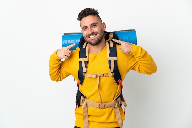Hombre joven alpinista con una gran mochila sobre aislado dando un pulgar hacia arriba gesto