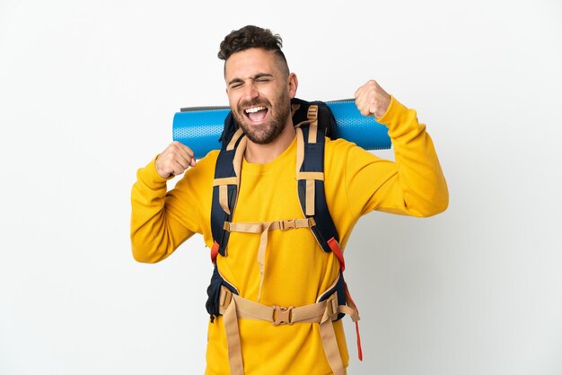 Hombre joven alpinista con una gran mochila sobre antecedentes aislados celebrando una victoria