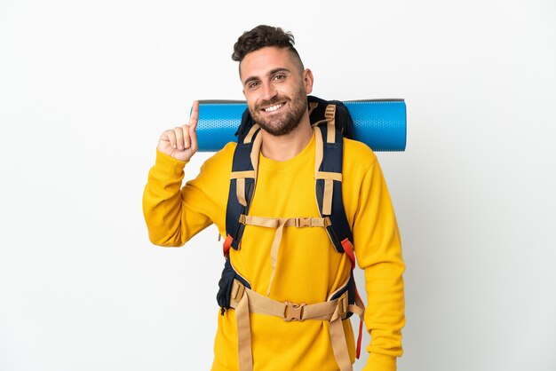 Hombre joven alpinista con una gran mochila sobre fondo aislado apuntando hacia una gran idea