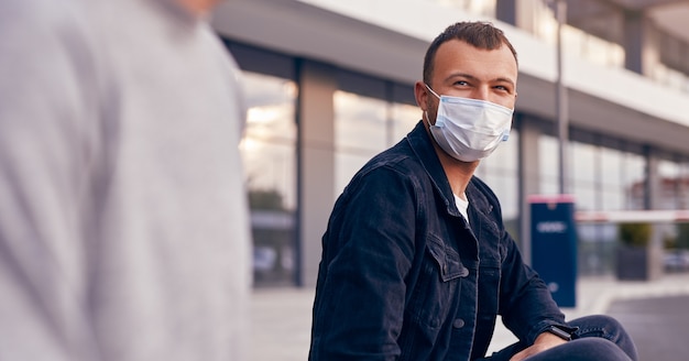 Hombre joven con un amigo descansando en la calle durante la epidemia