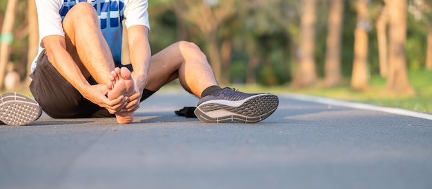 Foto hombre joven de la aptitud que lleva a cabo su lesión en la pierna de los deportes. dolor muscular durante el entrenamiento