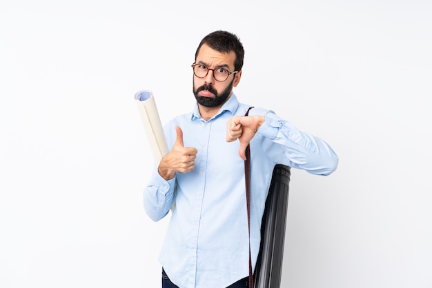 Hombre joven arquitecto con barba sobre pared blanca aislada haciendo buena mala señal. Indeciso entre sí o no