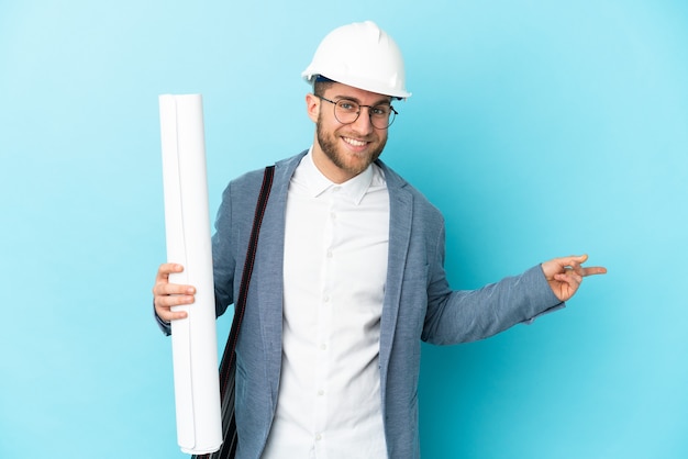 Hombre joven arquitecto con casco y sosteniendo planos aislados