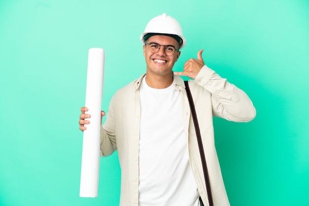 Foto hombre joven arquitecto sosteniendo planos sobre fondo aislado haciendo gesto de teléfono. llámame señal