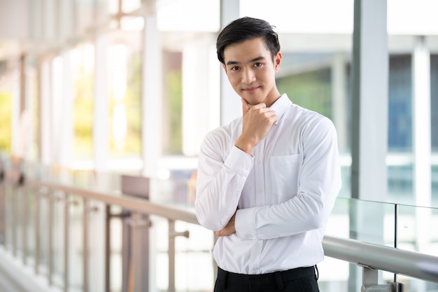 Hombre joven asiático hermoso confiado smilling en ciudad urbana.