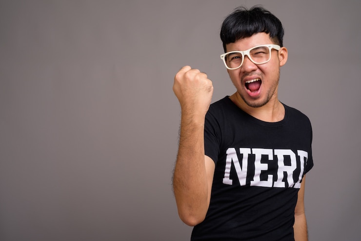 Foto hombre joven asiático nerd con anteojos contra gris