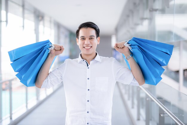 Hombre joven asiático que sostiene bolsos de compras