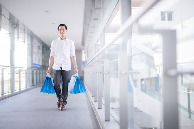 Hombre joven asiático que sostiene bolsos de compras