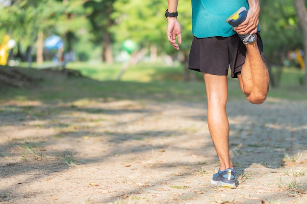 Hombre joven del atleta que estira en el parque al aire libre.