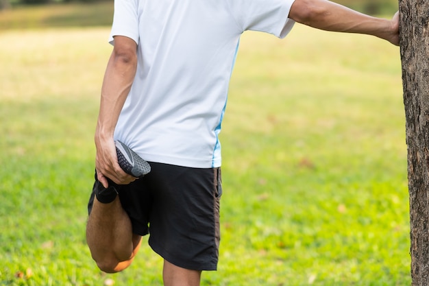 Hombre joven del atleta streching en el parque al aire libre.