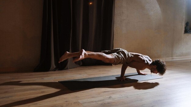 Foto un hombre joven y atlético hace yoga y realiza asanas