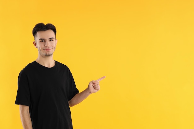 Hombre joven atractivo en camiseta sobre fondo amarillo