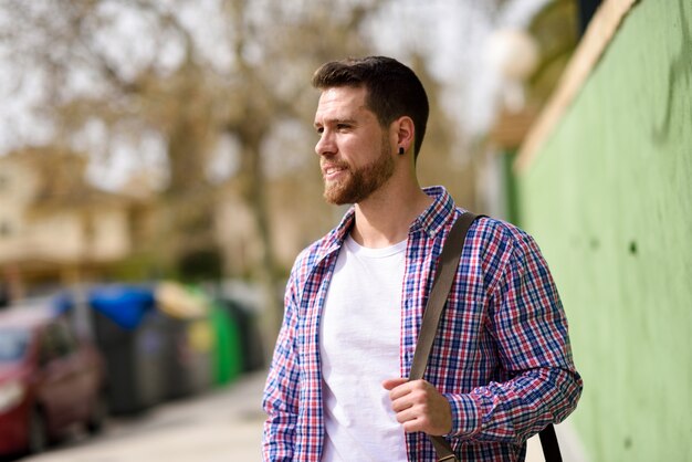 Hombre joven atractivo que se coloca en fondo urbano. Concepto de estilo de vida