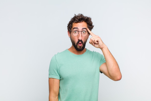 Hombre joven con barba que parece sorprendido, con la boca abierta, conmocionado, dándose cuenta de un nuevo pensamiento, idea o concepto