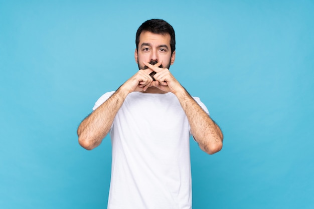 Hombre joven con barba sobre la pared azul aislada que muestra un gesto de silencio