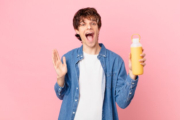 Hombre joven con un batido sintiéndose feliz y asombrado por algo increíble