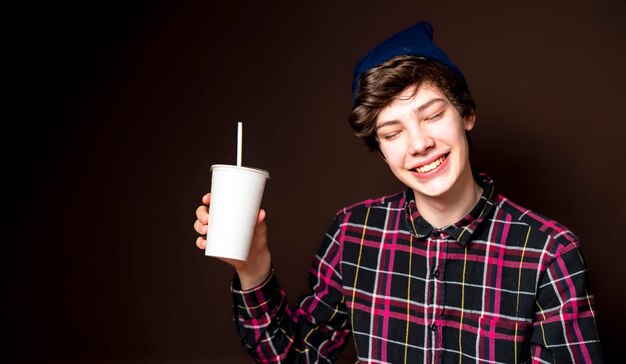 Hombre joven beber limonada sobre fondo oscuro aislado f