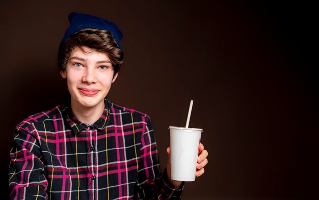 Hombre joven beber limonada sobre fondo oscuro aislado f