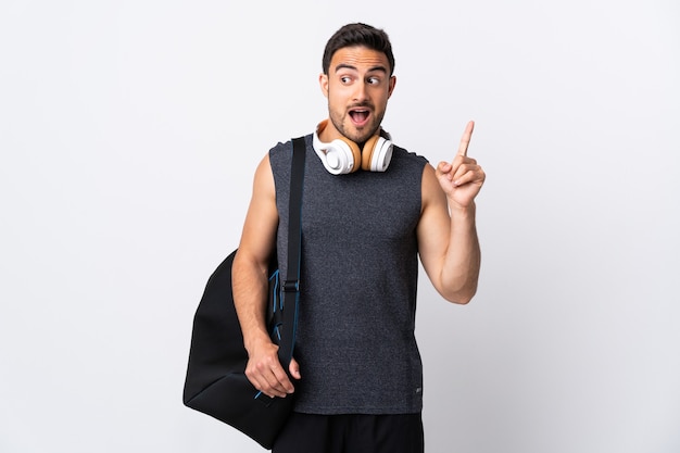 Hombre joven con bolsa de deporte aislado sobre fondo blanco con la intención de darse cuenta de la solución mientras levanta un dedo hacia arriba